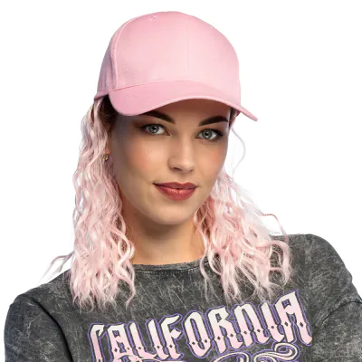 Woman wears a light pink baseball cap with a pink prui attached. Funny accessory for festivals or a bad party.