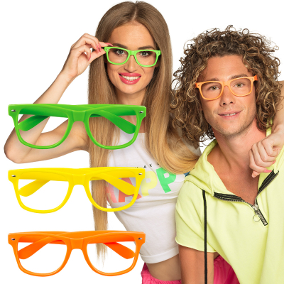 Vrouw met neon groene bril op, naast haar staat een man met een neon oranje bril op. Beide brillen zijn zonder glazen. Links van het stel zie je 3 neon brillen in groen, oranje en geel.