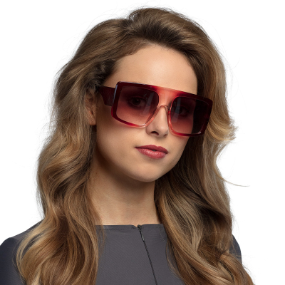 Woman with long dark blonde wavy hair wears large red retro party glasses with dark lenses and blocky frame.