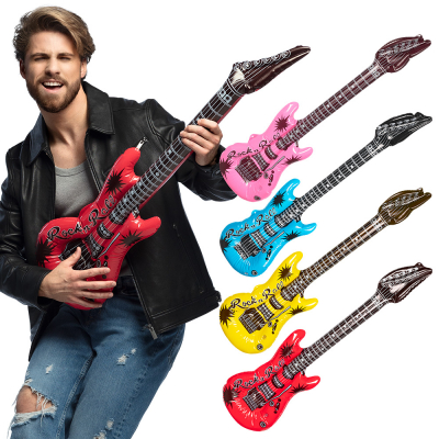 Man holding a red, inflatable rock guitar. Also shown are a pink, a blue, a yellow and a red inflatable guitar.