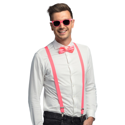 Lachende man draagt een witte blouse met donkere spijkerbroek in combinatie met een neon roze accessoireset bestaande uit een roze partybril, vlinderstrik en bretels.