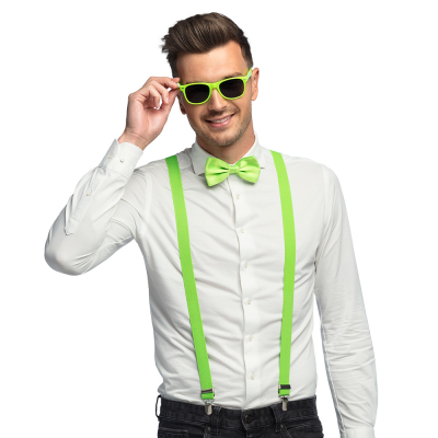 Lachende man draagt een witte blouse met donkere spijkerbroek in combinatie met een neon groene accessoireset bestaande uit een groene partybril, vlinderstrik en bretels.