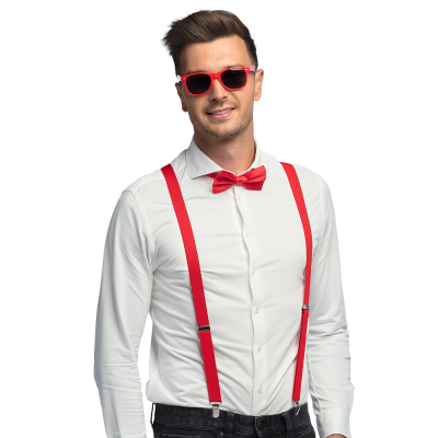 Lachende man draagt een witte blouse met donkere spijkerbroek in combinatie met een rode accessoireset bestaande uit een rode partybril, vlinderstrik en bretels.