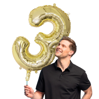 Golden foil balloon shaped as number 3.