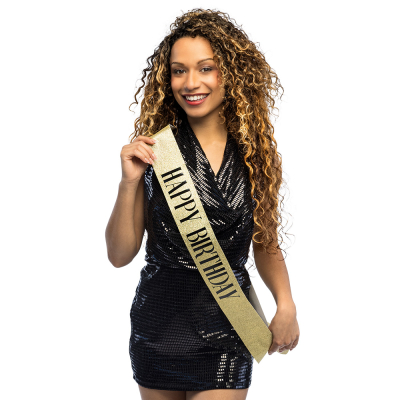 Femme souriante portant une écharpe souriante à paillettes dorées "Happy Birthday" avec des lettres noires dessus
