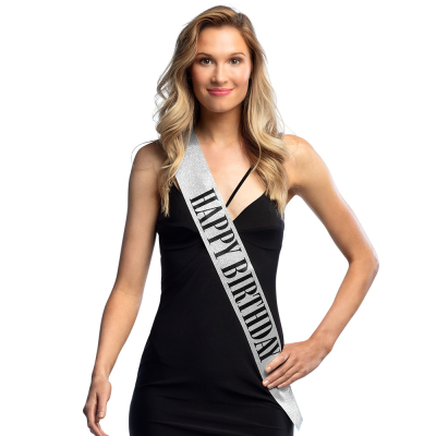 Smiling woman wearing a silver glitter Happy Birthday sash with black letters
