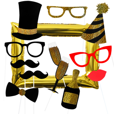 12 photo props of hats, glasses, bottle of champagne, glasses, moustaches, bow tie, mouth with a gold foil balloon in the shape of a photo frame behind it. 