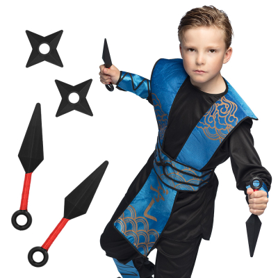 Boy dressed as a ninja in black/blue costume holding 2 kunais in his hand. Next to him you can see the kunais loose with 2 throwing stars next to them.