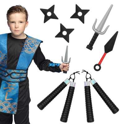 Boy dressed as a ninja in black/blue costume with a ninja dagger in his hand. Next to him, you can see the dagger loose with 2 nunchaku, 3 throwing stars and a kunai next to it.