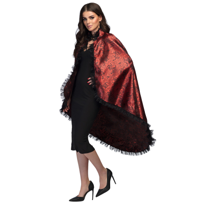 Vrouw in zwart gekleed draagt een zwierende, donkerrode, Halloween cape. De Halloween cape glanst, heeft een zwarte print en is afgewerkt met kant. 