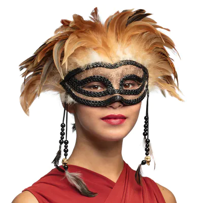 Une femme porte un masque vaudou saisissant avec un masque pour les yeux noir/brun décoré de hautes plumes brunes et de fils avec des perles sur les côtés, comme accessoire pour un costume d'Halloween mystérieux.