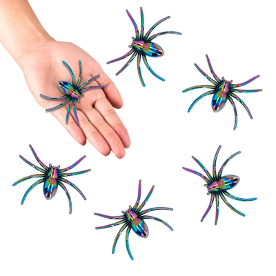6 shiny Halloween decoration spiders. 1 of the spiders lies on a hand.