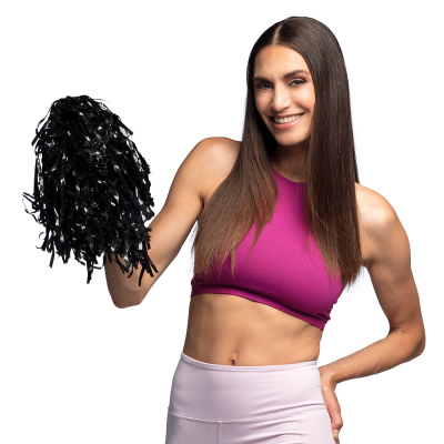 Lachende vrouw met lang steil bruin haar heeft een lichtroze sportbroek en roze sporttop aan en houdt een zwarte pompom vast.