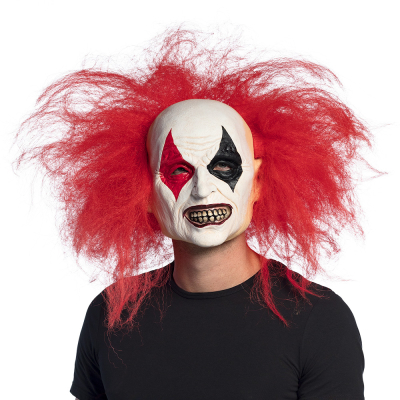 Man wearing a Halloween latex mask of a deranged laughing clown with messy red hair, large ears, white face and red and black patterns around the eyes.