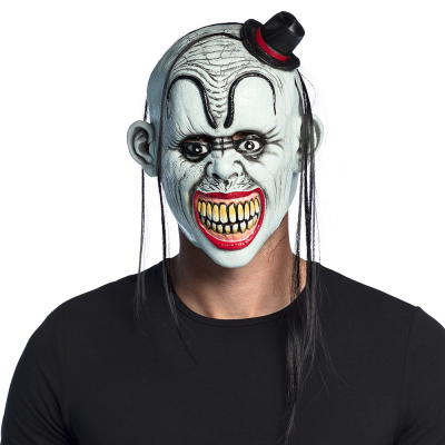 Homme portant un masque d'halloween en latex représentant un clown dérangé avec un large sourire, un visage blanc, des sourcils bizarres, une tête chauve avec quelques longues mèches de cheveux et un petit chapeau.