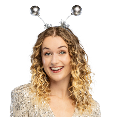 A smiling woman is wearing a silver sequinned top and on her head she wears a festive tiara with two moving silver glittery balls.