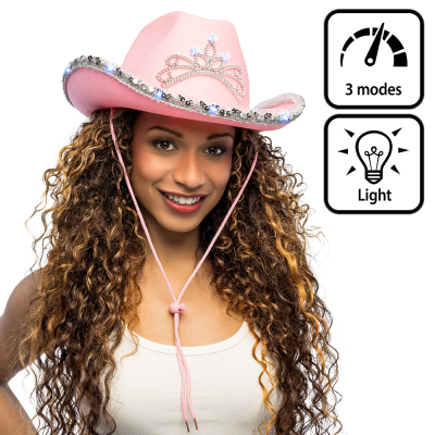 A smiling woman is wearing a light pink cowboy hat, decorated at the front with a tiara that lights up and, around the brim, a glittery band with built-in LED lighting.