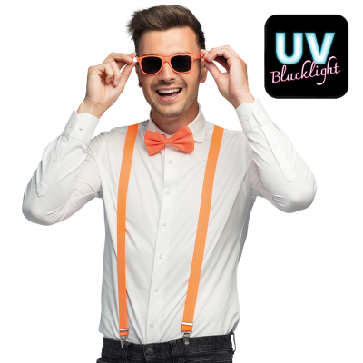 Lachende man draagt een witte blouse met donkere spijkerbroek in combinatie met een neon oranje accessoireset bestaande uit een oranje partybril, vlinderstrik en bretels.