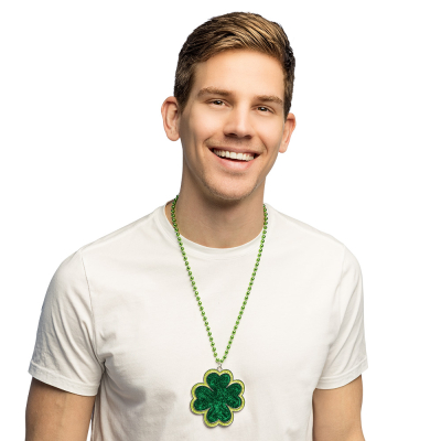 A cheerful man is wearing a white T-shirt and has a long green necklace with a large St Patrick’s Day four-leaf clover charm attached to it.