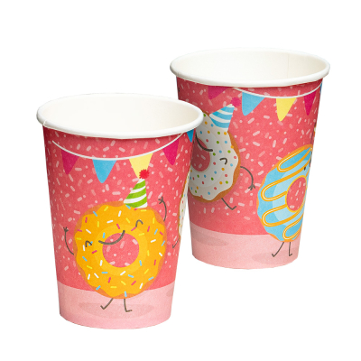 2 roze papieren bekertjes met erop een feestende donuts in verschillende kleuren en allemaal een feesthoedje op.