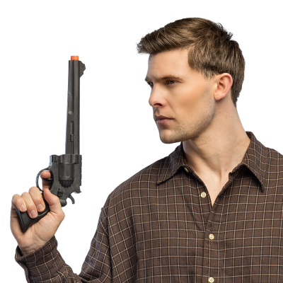 Un jeune homme porte une chemise western marron foncé et tient un faux pistolet noir classique du Far West pour compléter son look de cow-boy dur.