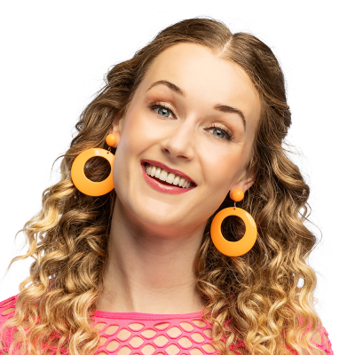 Une femme souriante porte un t-shirt rétro en maille rose fluo et arbore des boucles d’oreilles des années 80 orange fluo composées de grands anneaux ronds.