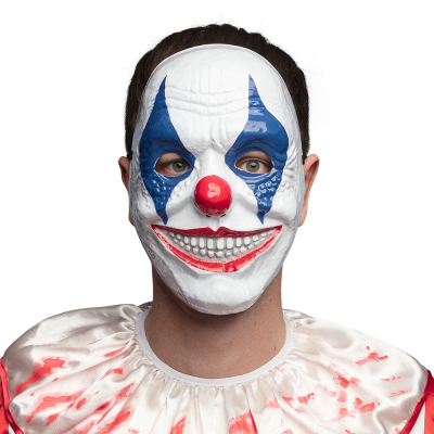 Un homme porte un costume d'Halloween de clown d'horreur sanglant, accessoirisé d'un masque de clown d'horreur avec un visage blanc, des accents bleus autour des yeux, des lèvres rouges et un nez rond rouge.