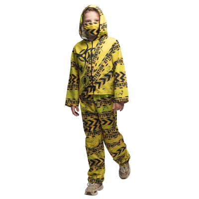 A little boy wears a radioactive Halloween costume consisting of a yellow jacket with a hood and long trousers with radioactive icons and warning texts printed on them and a matching face mask.