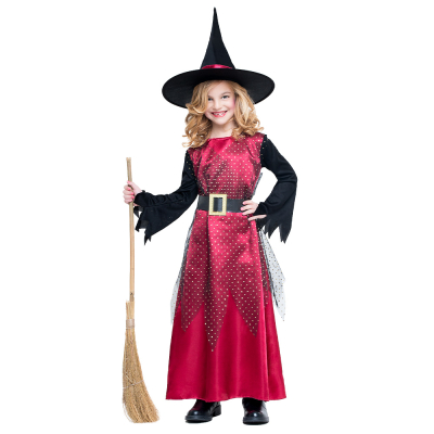 Une fille porte un costume de sorcière pour Halloween, composé d'une longue robe rouge à manches longues noires, d'un gilet en tulle à pois pour recouvrir la robe, d'une large ceinture noire et d'un chapeau de sorcière noir assorti avec des accents de mét
