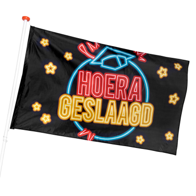Grote zwarte vlag aan een vlaggenstok met erop Hoera Geslaagd in rode en gele neon letters, een doctoraalmutsje in neon blauw en sterren als versiering.