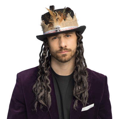A man wears a tall voodoo hat with feathers, skull details and long black dreadlocks.