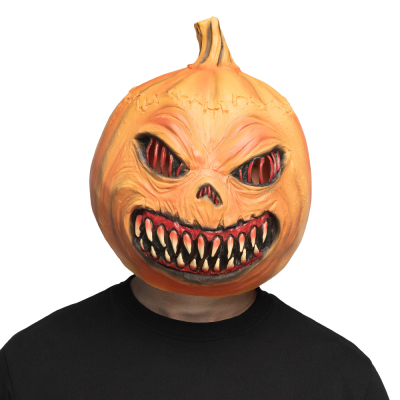 Un homme portant un t-shirt noir a sur la tête un masque d'Halloween en latex représentant une citrouille monstrueuse avec de grands yeux et un sourire effrayant avec des dents effrayantes.